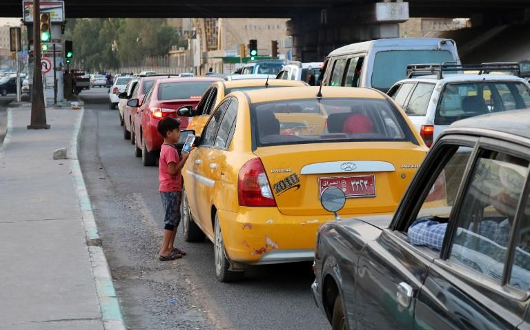 طفل في مدينة الموصل العراقية يبيع قارورة ماء لسائق سيارة أجرة، 7 يوليو 2018. وليد الخالد/أ ف ب