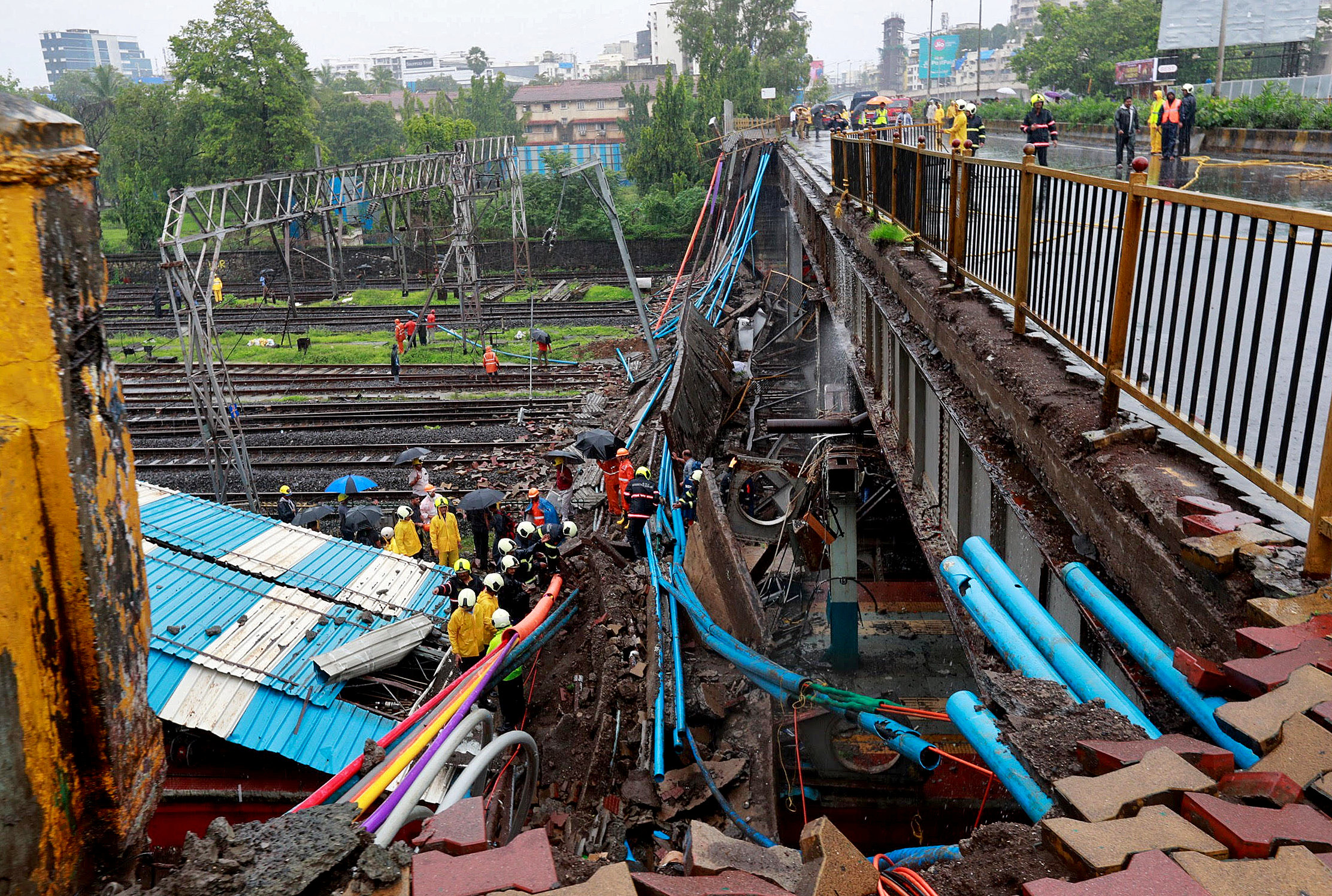عمال الإنقاذ ينظرون إلى العمل في موقع جسر فوق الأرض الذي انهار فوق خطوط السكك الحديدية. رويترز