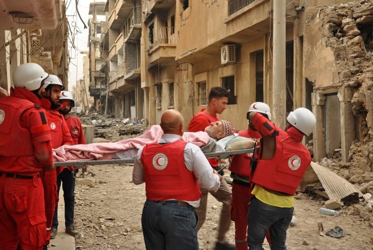 صورة أرشيفية لطواقم إسعاف تخلي مصاباً في مدينة دير الزور. أ ف ب  