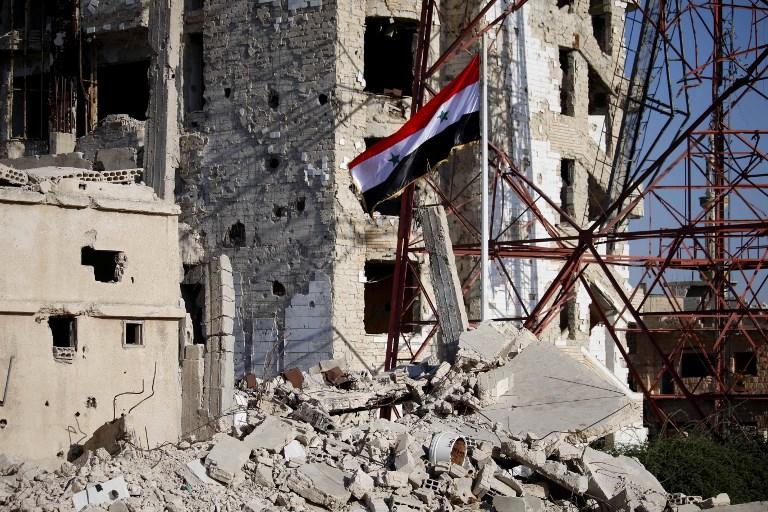 العلم السوري وسط مباني مدمرة في درعا البلد. محمد أبا زيد/أ ف ب