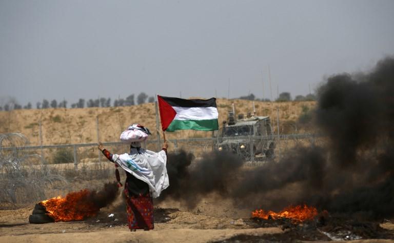 امرأة تحمل العلم الفلسطيني شرق خان يونس قرب حدود غزة. 8 يونيو 2018. سعيد خطيب/ ا ف ب