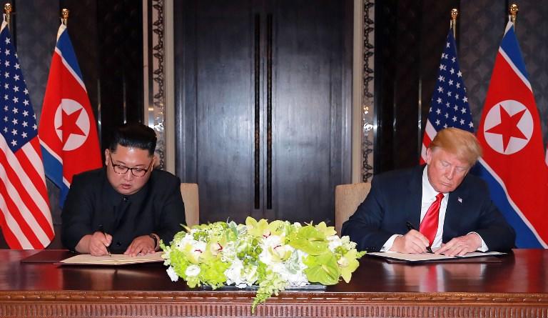 صورة للرئيس الأميركي دونالد ترامب وزعيم كوريا الشمالية كيم جونغ أون يوقعان وثائق في قمة سنغافورة. نشرتها وكالة الأنباء المركزية الكورية في 13 يونيو 2018. ا ف ب