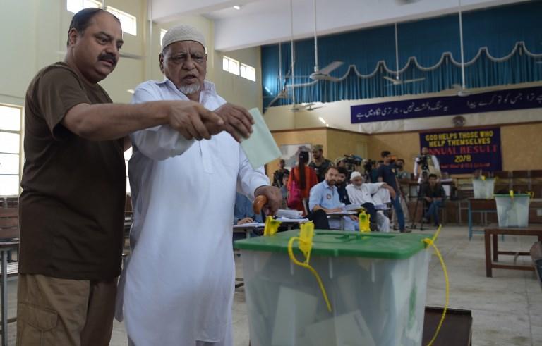 رجل باكستاني يساعد والده الكفيف على الإدلاء بصوته في مركز اقتراع خلال الانتخابات في إسلام أباد. 25 يوليو 2018. ا ف ب