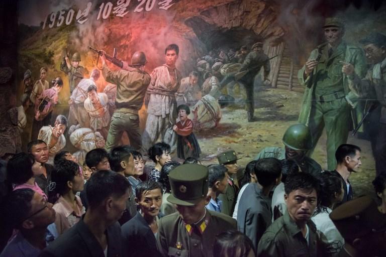 كوريون شماليون يشاهدون لوحة تظهر جنوداً أميركيين يستعدون لقتل كوريين شماليين في متحف سينشون جنوبي بيونغ يانغ. الصورة التقطت في 24 يوليو 2017. ا ف ب 
