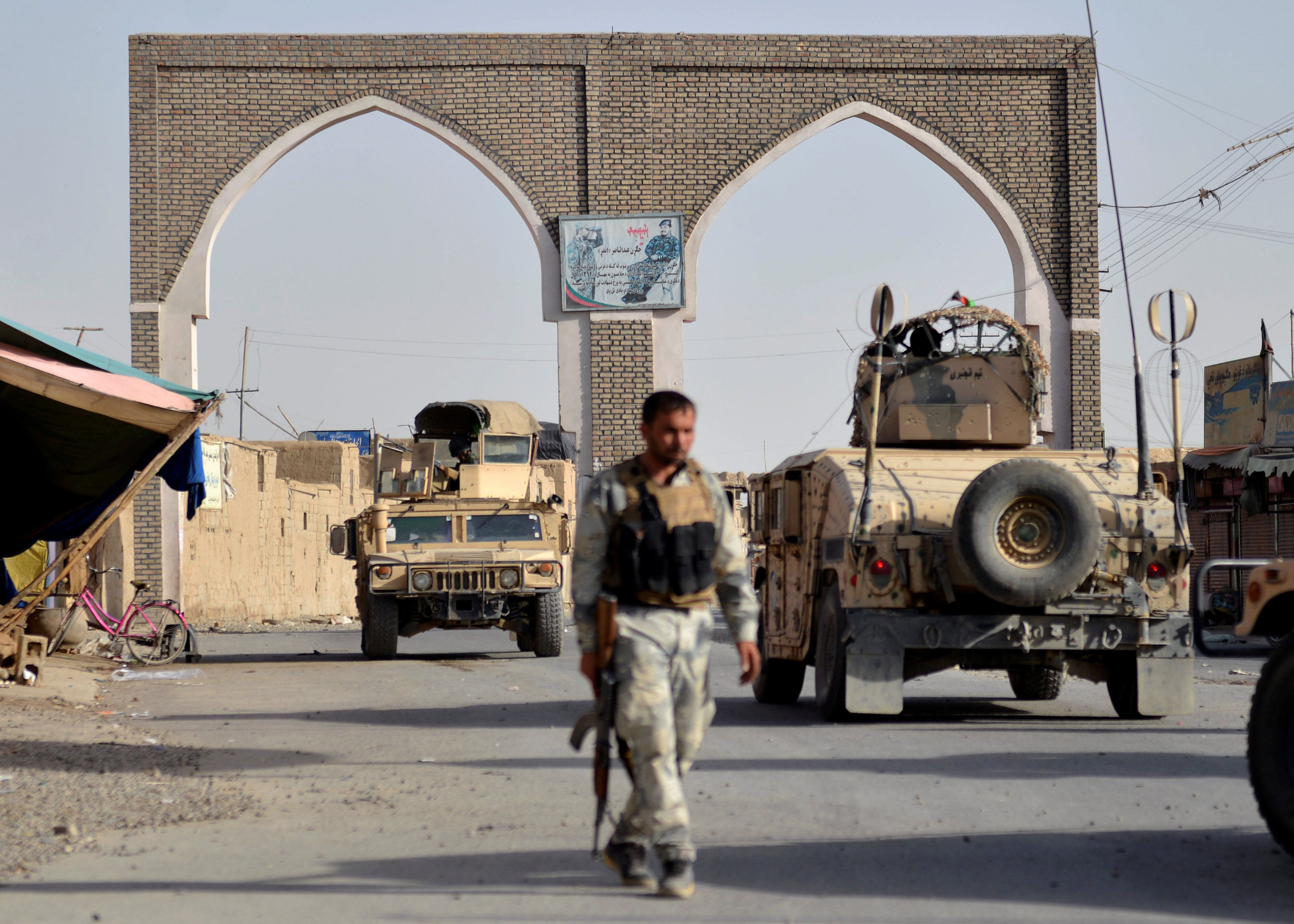 رجل أمن أفغاني يمر بمحاذاة مركبات عسكرية في وقت ينفذ فيه متشددو طابان هجمات أسفرت عن سقوط قتلى، 12 أغسطس 2018. رويترز 