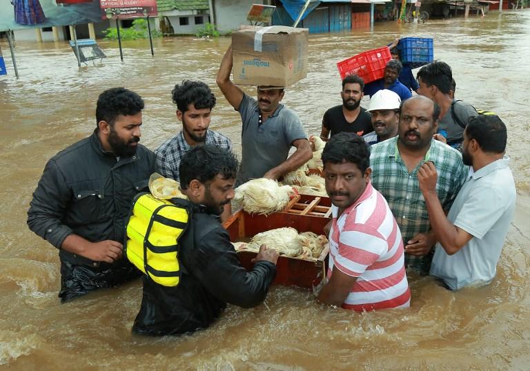 أشخاص من ولاية كيرالا الهندية التي تشهد فيضانات يحاولون النجاة من تجمع للمياه. أ ف ب 