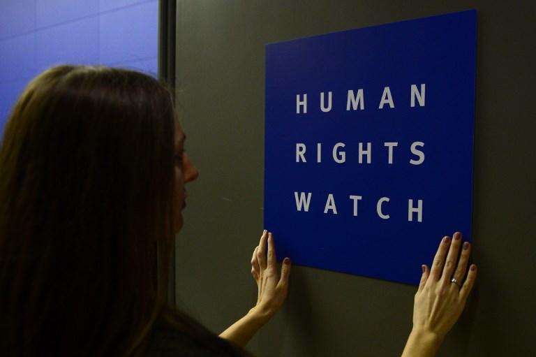 امرأة تضع شعار منظمة حقوق الإنسان على الباب عندما تقوم بإعداد الغرفة قبل المؤتمر الصحفي لإصدار تقريرها السنوي العالمي في 21 يناير 2014 في برلين. جون ماكدوغال/ أ ف ب
