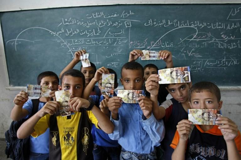 يعرض طلاب المدارس الابتدائية الفلسطينية أموال تلقوها من وكالة الأمم المتحدة لإغاثة وتشغيل اللاجئين الفلسطينيين، جنوب قطاع غزة، 15 سبتمبر 2009. سعيد خطيب/ أ ف ب