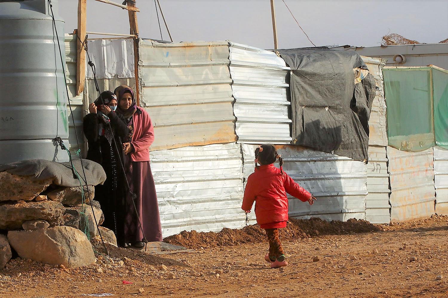 طفلة تتجه نحو أمها التي تقف بجانب منزلهم المصنوع من الحديد في مخيم الزعتري في محافظة المفرق شمالي الأردن. صلاح ملكاوي/ المملكة