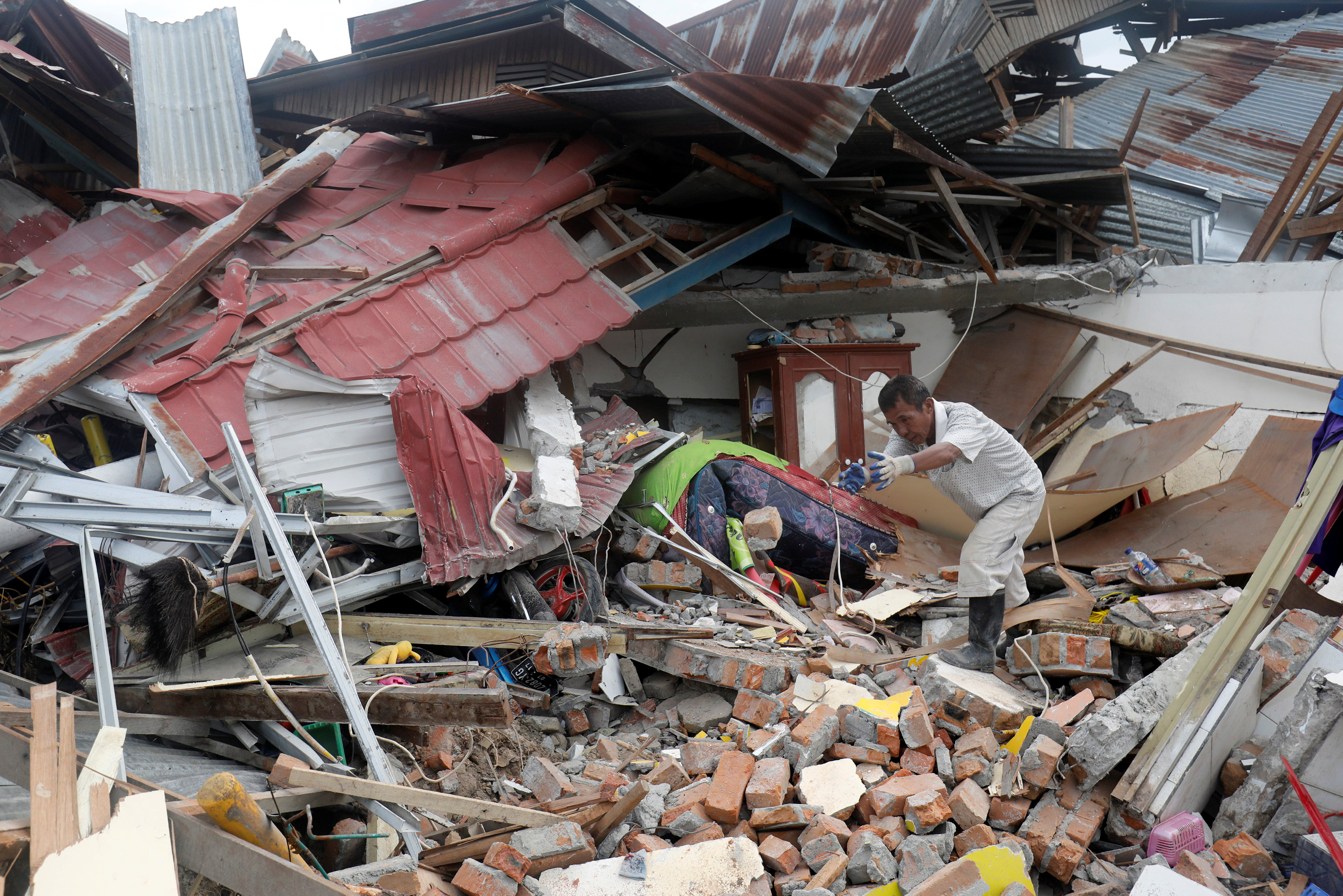 رجل يحاول إزالة حطام منزله المنهار إثر الزلزال في سولاويسي في إندونيسيا، 11 أكتوبر 2018. دارين وايتسايد/ رويترز