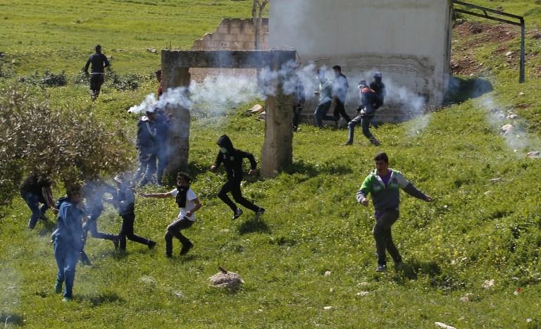 صورة أرشيفية لشبان فلسطينيين يهربون من قنابل الغاز الإسرائيلية. أ ف ب 