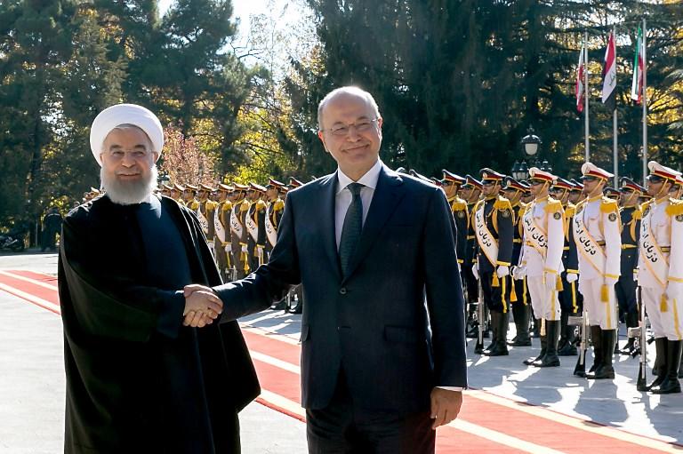 الرئيس العراقي برهم صالح (يمين)، مصافحاً الرئيس الإيراني حسن روحاني (يسار) في العاصمة الإيرانية طهران. أ ف ب
