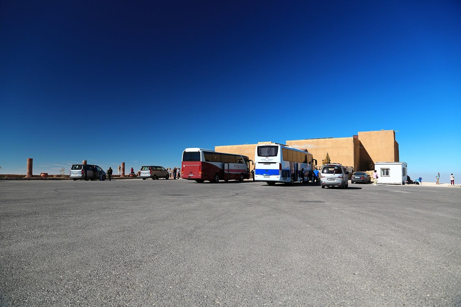 حافلات نقل سياحي متوقفة أمام استراحة على الطريق الصحراوي المؤدي لجنوب الأردن. (Shutterstock) 