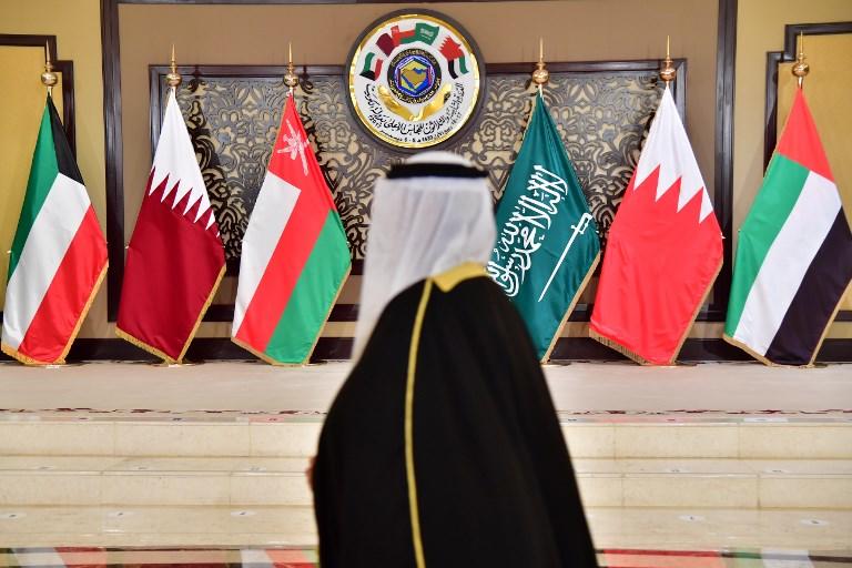 رجل يسير أمام منصة تحمل أعلام دول مجلس التعاون الخليجي. (أ ف ب)