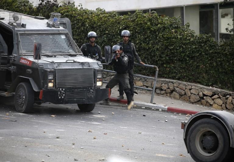 أفراد من الجيش الإسرائيلي يطلقون الغاز المسيل للدموع على شبان فلسطينيين خلال مواجهات في مدينة رام الله، 30 سبتمبر 2018. عباس مومني/ أ ف ب 