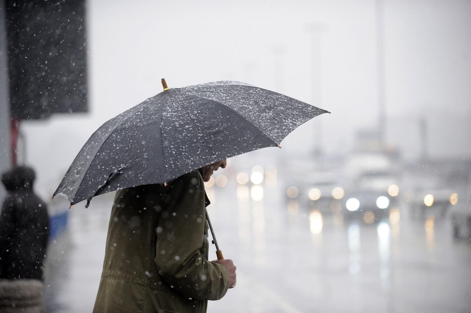 رجل يحمل مظلة ليحمي نفسه من المطر. (shutterstock)