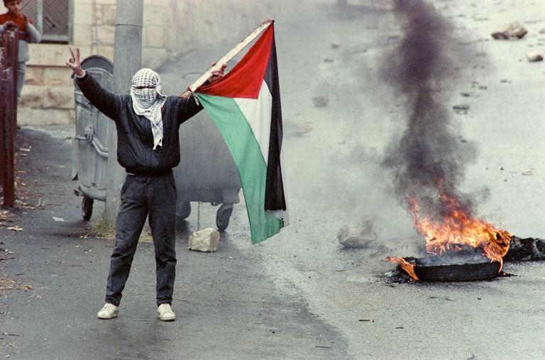 متظاهر يرفع العلم الفلسطيني في نابلس في مواجهة جنود الاحتلال خلال الانتفاضة الأولى، 12 يناير 1988. سفين ناكستراند/ أ ف ب