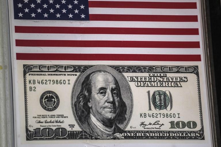 صورة أرشيفية تظهر علمًا أميركياً وملصق أوراق نقدية بقيمة 100 دولار أمريكي في أحد مكاتب الصرافة. أ ف ب