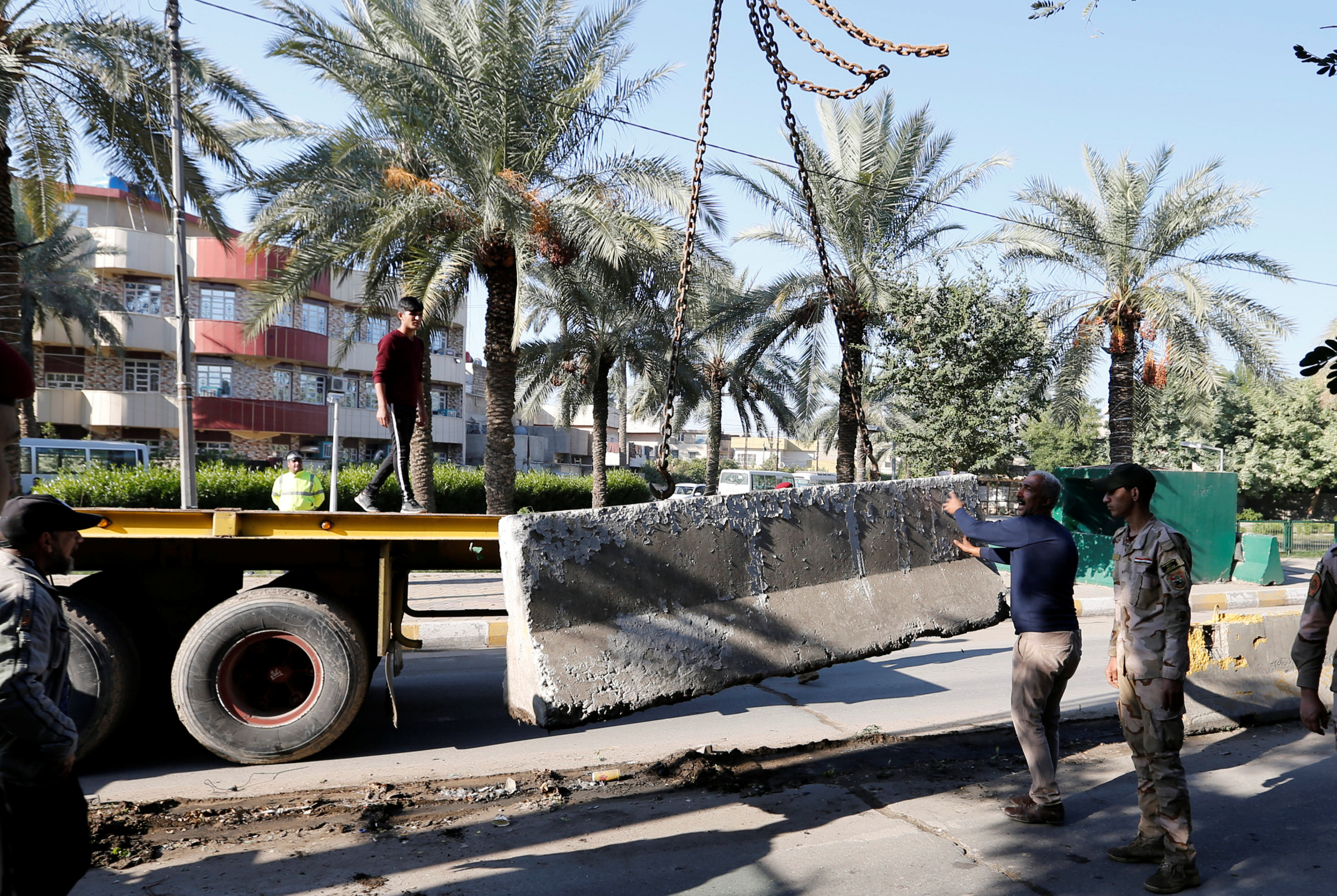 قوات الأمن العراقية والعمال يستخدمون رافعة لإزالة حاجز إسمنتي في شارع مؤدي للمنطقة الخضراء في بغداد. 28  نوفمبر 2018. رويترز
