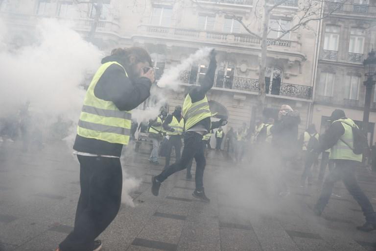 أحد متظاهري السترات الصفراء يلقي عبوة غاز مسيل للدموع في باريس في 8 ديسمبر 2018. أ ف ب