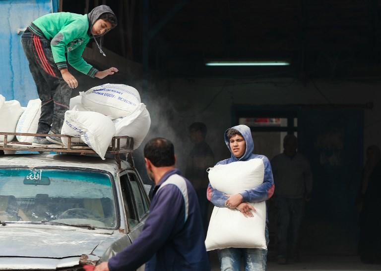 فلسطينيون يحملون أكياس طحين استلموها من منظمة تابعة للأمم المتحدة. (أ ف ب)