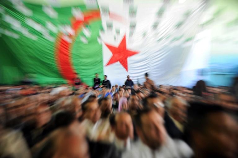 علم الجزائر على حائط خلف مشاركين في الانتخابات الرئاسية. 24 مارس 2014. أ ف ب