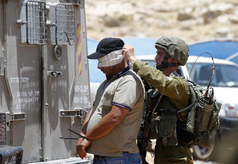 صورة أرشيفية لجندي إسرائيلي يعتقل فلسطينيا في الضفة الغربية. أ ف ب 