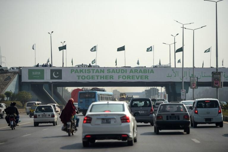 مركبات تسير في شارع عام في باكستان تحت جسر معلق عليه لافتة ترحب بولي العهد السعودي محمد بن سلمان الذي يزور البلاد. 15 فبراير 2019. أ ف ب 