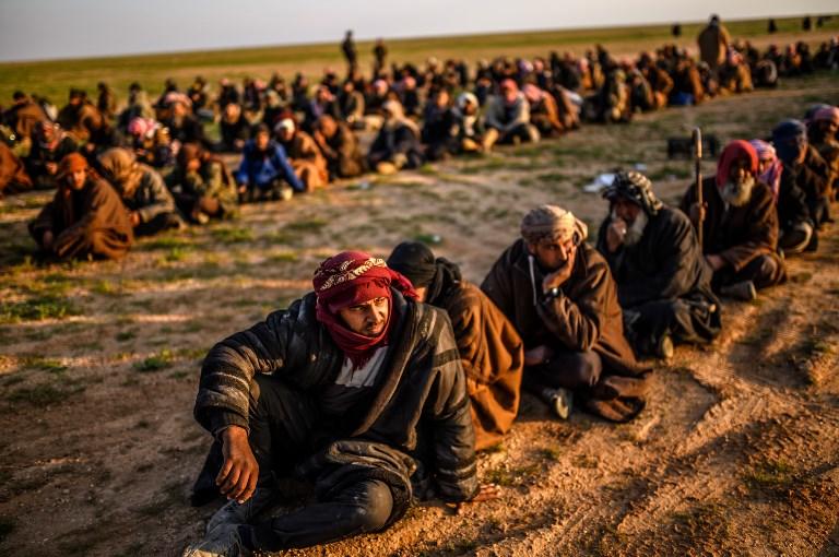 أشخاص يشتبه أنهم من تنظيم "داعش"ينتظرون تفتيشهم من قوات سوريا الديمقراطية في سوريا. 22 فبراير 2019. بولنت كيليك / أ ف ب