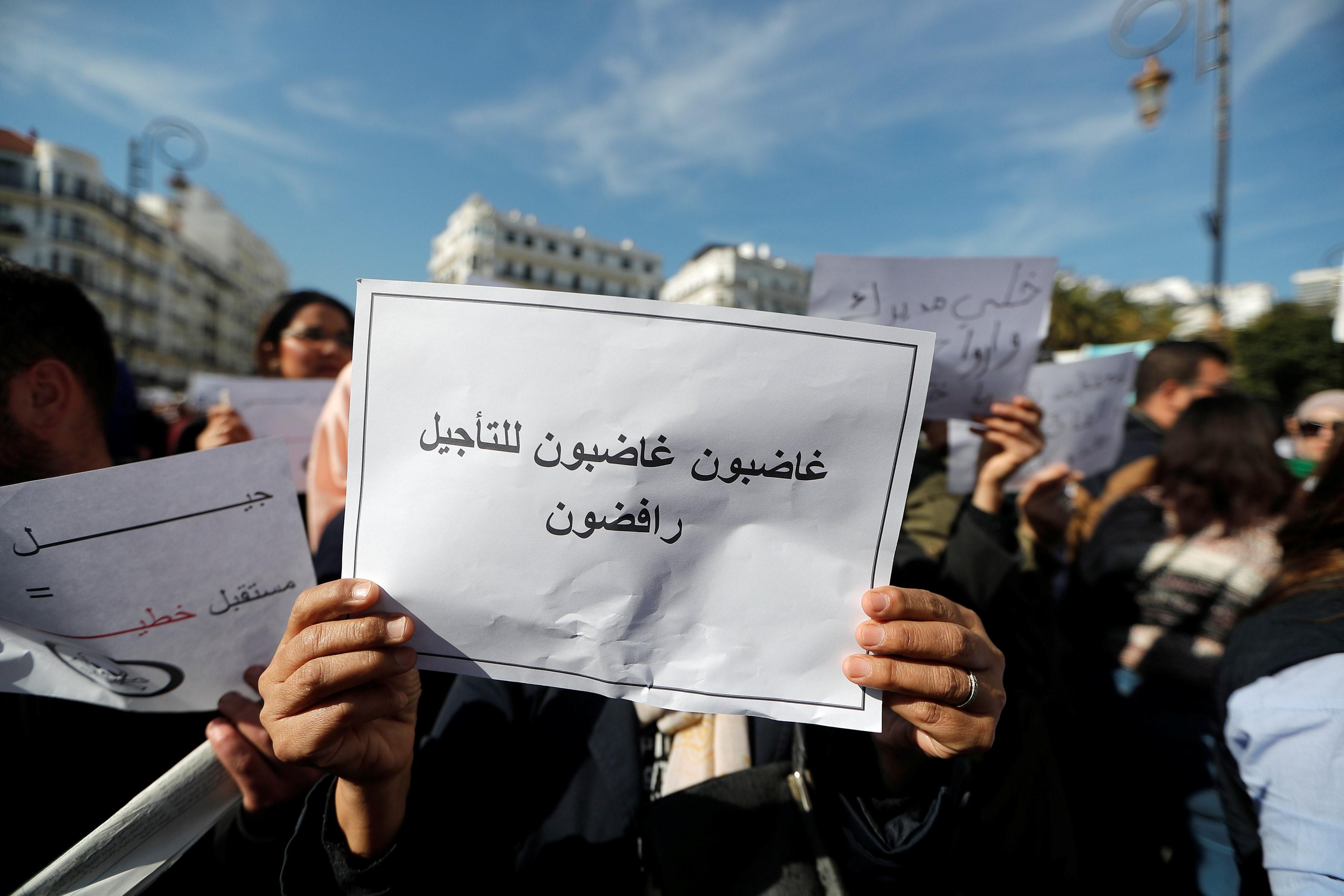 محتجون جزائريون يحملون لافتات رافضة لتأجيل الانتخابات الرئاسية، 13 مارس 2019. رويترز 