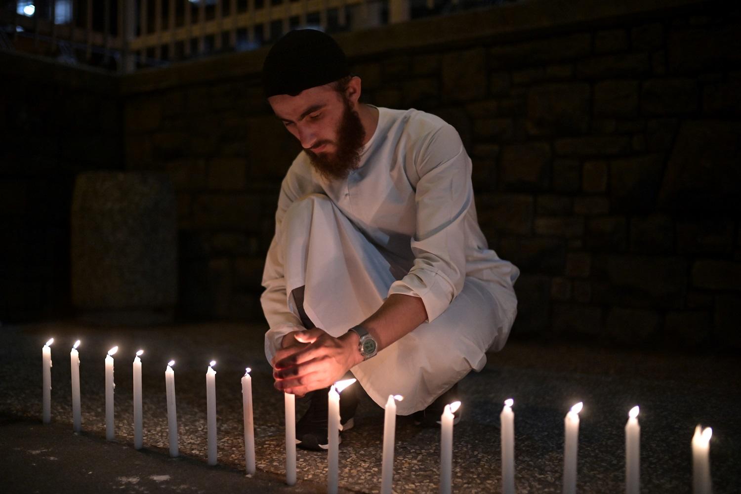 رجل يضيء 49 شمعة قرب مستشفى "كرايستشيرش" استذكارا لضحايا الاعتداء الإرهابي على مسجدين في نيوزيلندا، 16 مارس 2019. أ ف ب 
