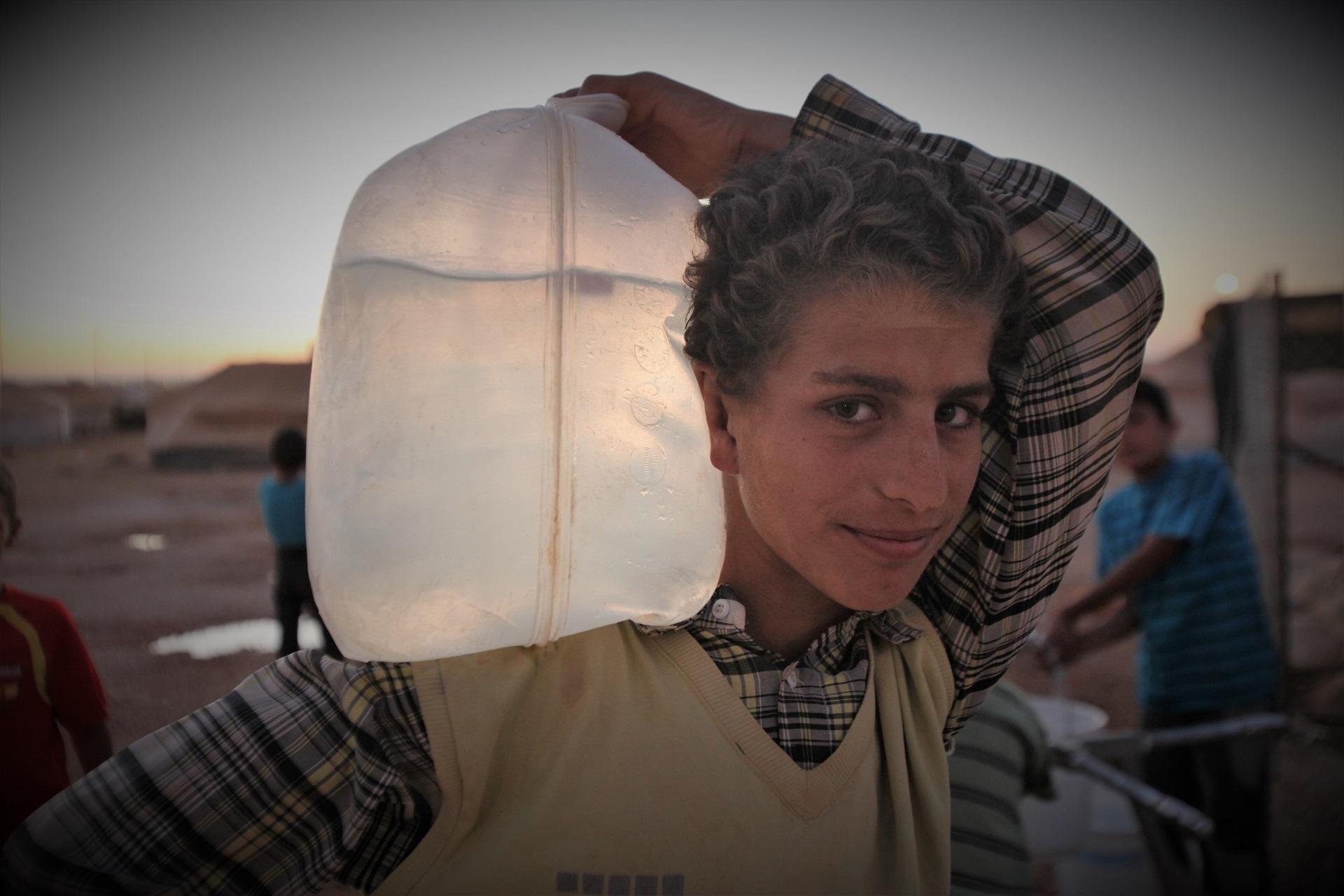 لاجئ يحمل على كتفه ماء معبأ في كيس في مخيم الزعتري للاجئين في محافظة المفرق شمالي الأردن. صلاح ملكاوي/ المملكة