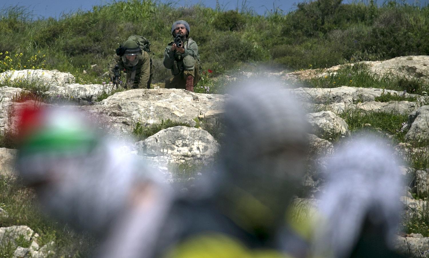 جنود من جيش الاحتلال يصوّبون أسلحتهم تجاه فلسطينيين يحتجون على مصادرة أراضيهم في قرية كفر قدوم قرب مدينة نابلس، 22 مارس 2019. جعفر استيتية، أ ف ب 