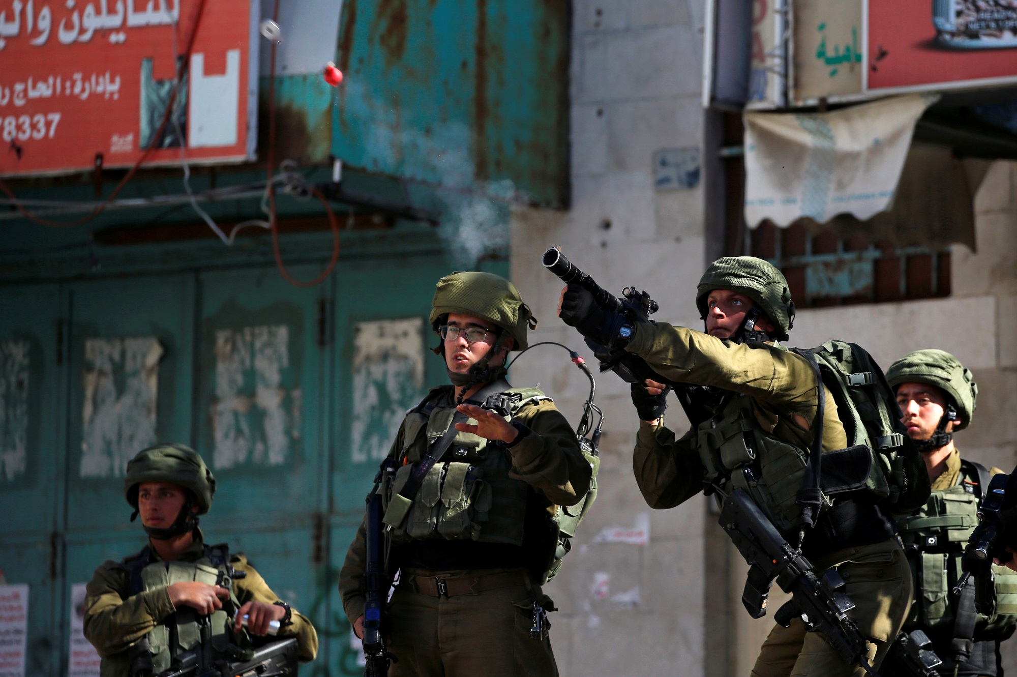 جندي من جيش الاحتلال الإسرائيلي يطلق قنابل غاز باتجاه فلسطينيين في الخليل، 12 أبريل 2019. رويترز