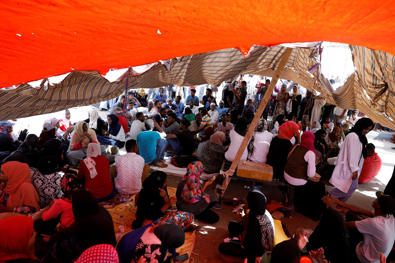 سودانيون مشاركون في الاحتجاجات أمام وزارة الدفاع يجلسون تحت مظلة للاحتماء من أشعة الشمس، 25 أبريل 2019. رويترز 