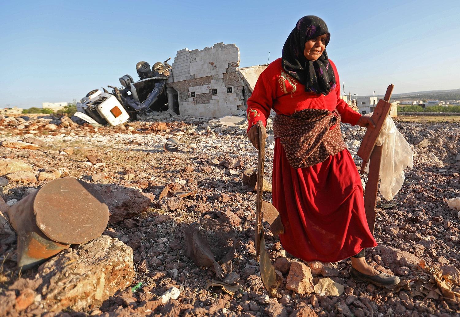 امرأة تجمع حطاما من منزلها الذي دمرته غارات روسية على مناطق في إدلب السورية، 20 مايو 2019. عمر حاج خضور/ أ ف ب 