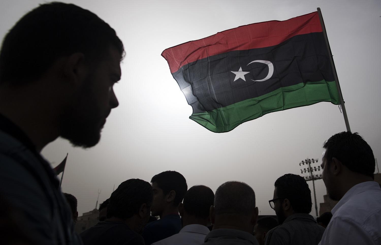 مقاتلون ينتمون لقوات الحكومة المدعومة دوليا يرفعون علم ليبيا خلال جنازة أحد المقاتلين، 24 أبريل 2019. أ ف ب 