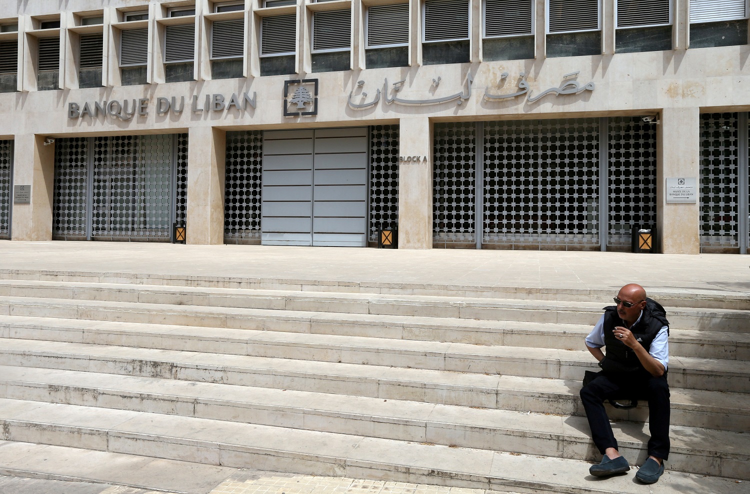 رجل يجلس أمام مصرف لبنان. صافي الأصول الأجنبية للبنك المركزي اللبناني هبط إلى 37.3 مليار دولار في مايو، مقارنة بـ 42.9 مليار دولار قبل عام. رويترز 