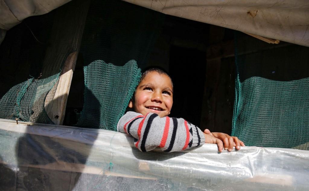 طفل سوري لاجئ ينظر من داخل خيمة في مخيم للاجئين في قرية المحمرة في منطقة عكار شمالي لبنان. 9 آذار/ مارس 2019. إبراهيم شلهوب/ أ ف ب