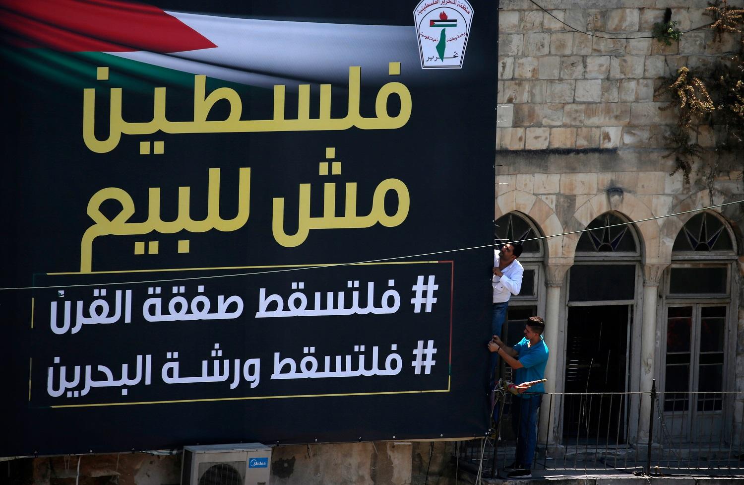 فلسطينيون يثبتون لافتة كتب عليها "فلسطين ليست للبيع" ، في الساحة الرئيسية لمدينة نابلس بالضفة الغربية. 24 يونيو 2019. أ ف ب