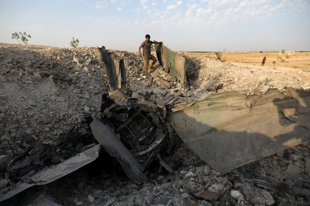 مقاتل من المعارضة يقف قرب بقايا طائرة حربية تابعة للحكومة بالقرب من بلدة خان شيخون جنوبي محافظة إدلب، 14 أغسطس 2019. (عمر الحاج قدور/ أ ف ب)