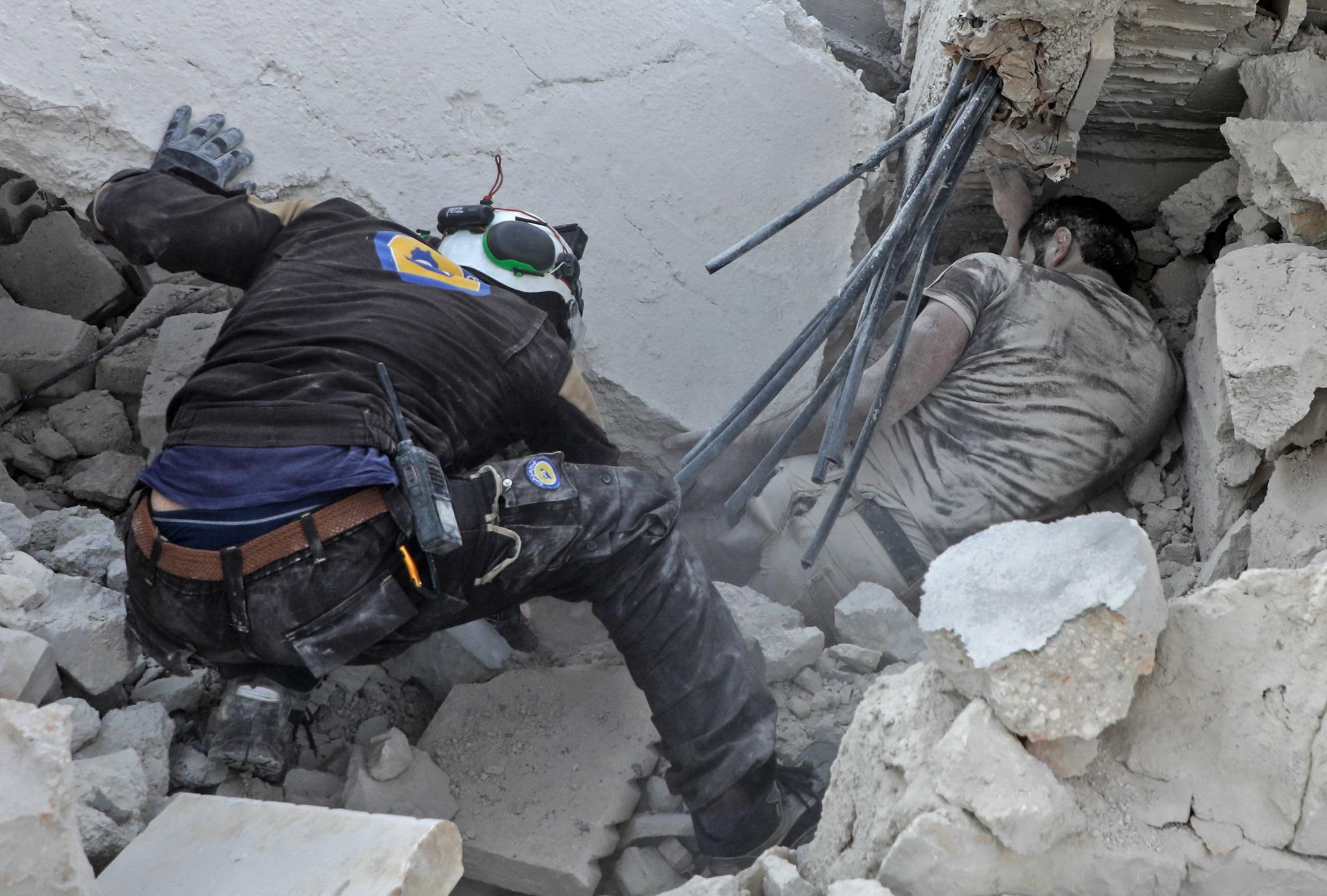 رجال الخوذ البيضاء يحاولون إنقاذ أشخاص تحت الأنقاذ بعد قصف. أ ف ب 