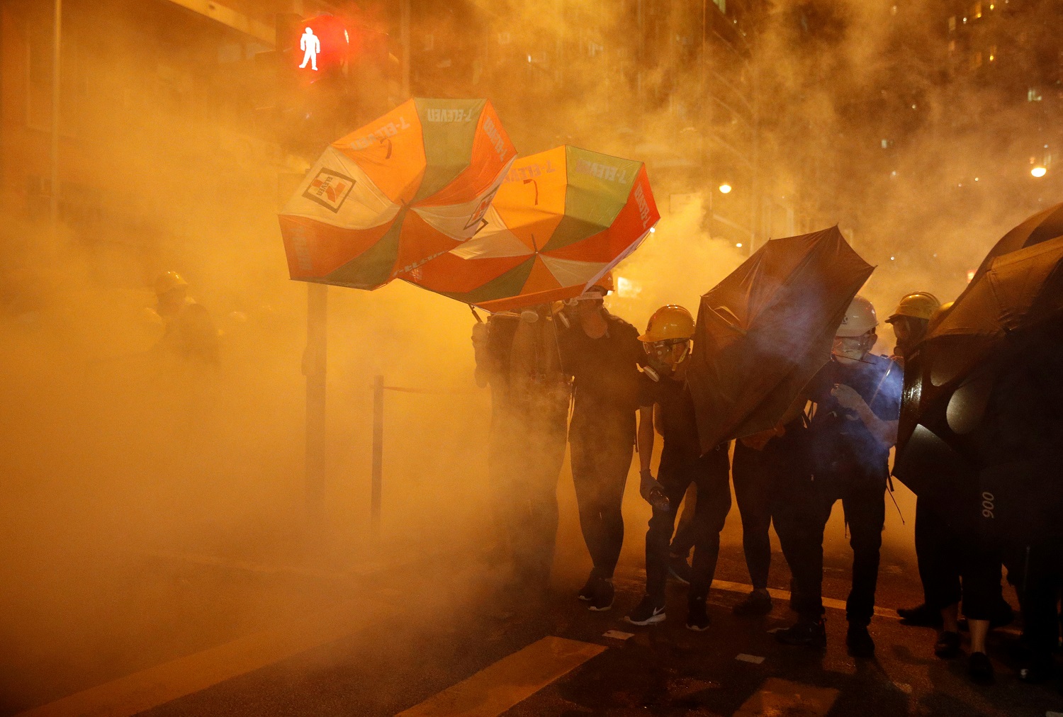 محتجون في هونغ كونغ يحاولون حماية أنفسهم من غاز مسيل للدموع أطلقته قوّات الشرطة، 28 يوليو 2019. رويترز 