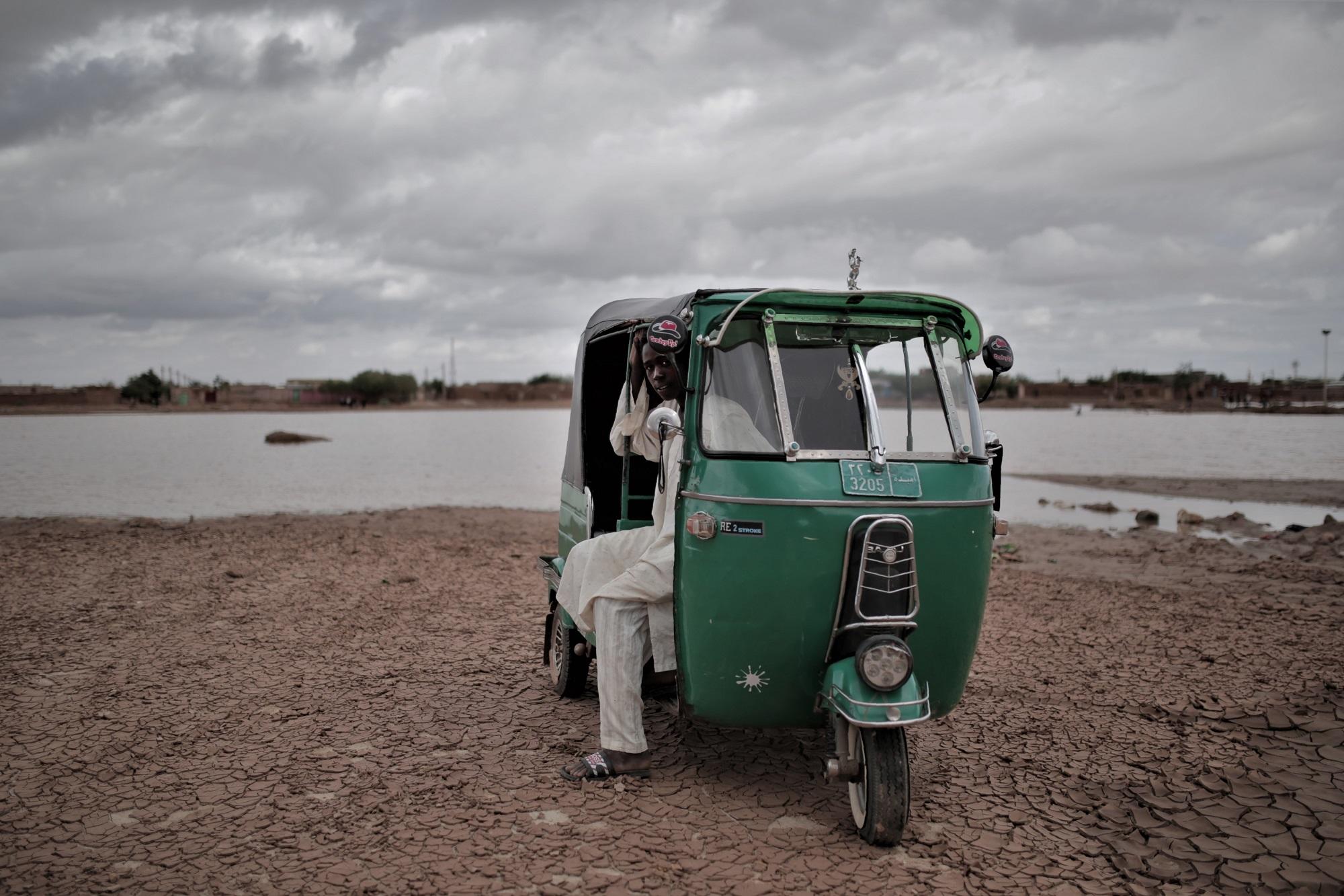 شاب سوداني ينتظر المساعدة بعدما حاصرته مياه الأمطار في أمدرمان. أ ف ب 