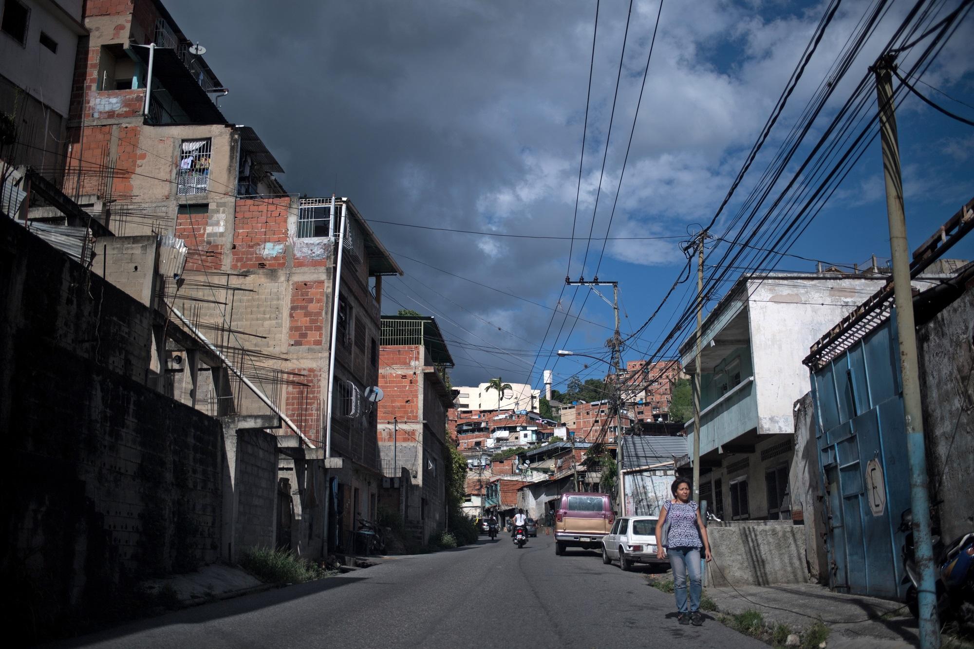 امرأة تسير في شوارع حي بيتاري في كاراكاس في وقت تشهد فيه فنزويلا أزمة سببها هجرة ترك الآباء أطفالهم لتأمين تكاليف معيشتهم. 9 أغسطس 2019. (أ ف ب)
