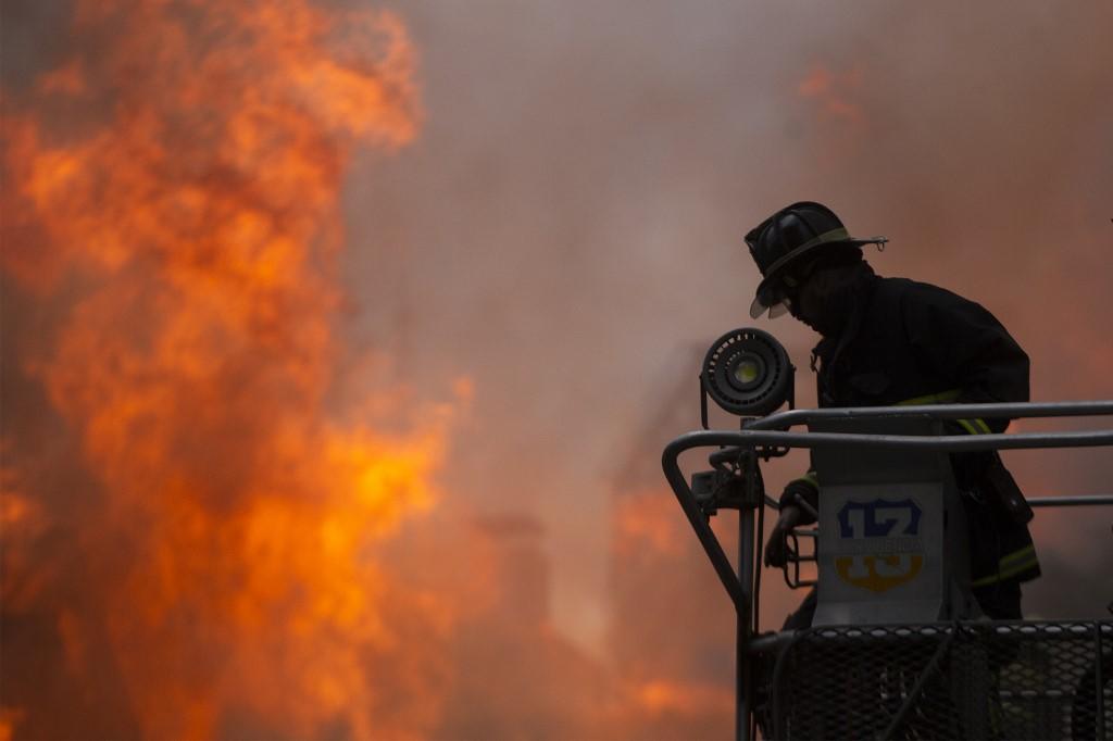 رجل إطفاء يُخمد حريقاً شب في جامعة بيدرو دي فالديفيا في العاصمة التشيلية سانتياغو. (كلاوديو رييس/ أ ف ب)
