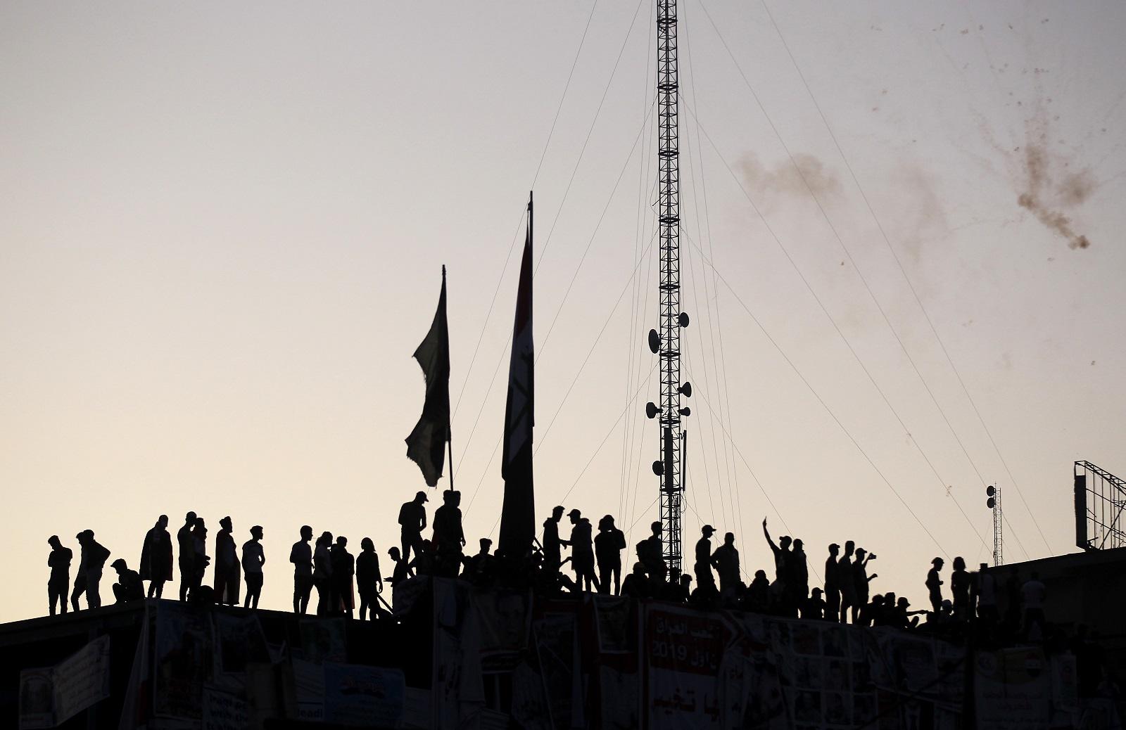 متظاهرون عراقيون يتجمعون فوق مبنى في ميدان التحرير ببغداد. 8 نوفمبر 2019. (أ ف ب)