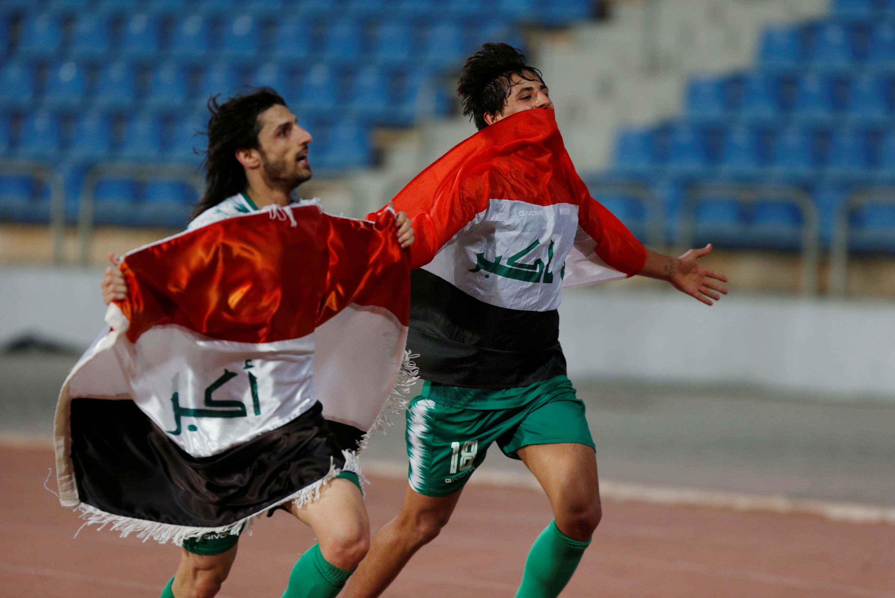 لاعبان من المنتخب العراقي يحتفلان بهزيمة المنتخب الإيراني في ستاد عمان الدولي. (رويترز)