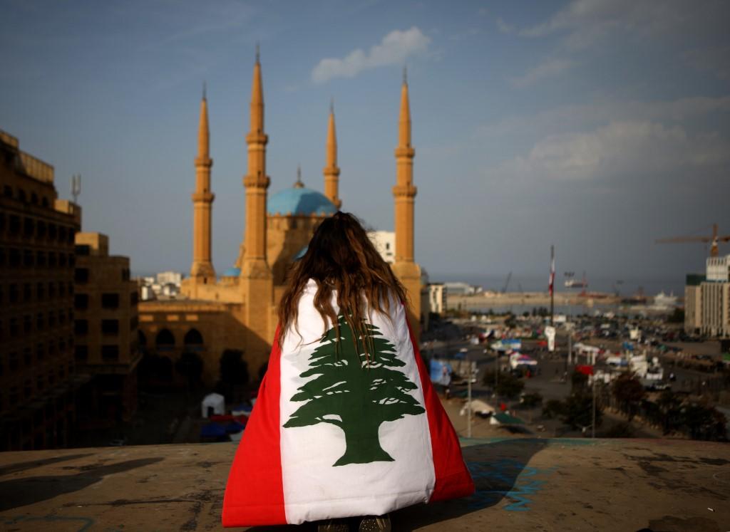 متظاهرة تقف على بناية مقابل مسجد محمد الأمين وسط العاصمة اللبنانية بيروت، 14 تشرين الثاني/نوفمبر 2019. (باتريك باز/ أ ف ب)