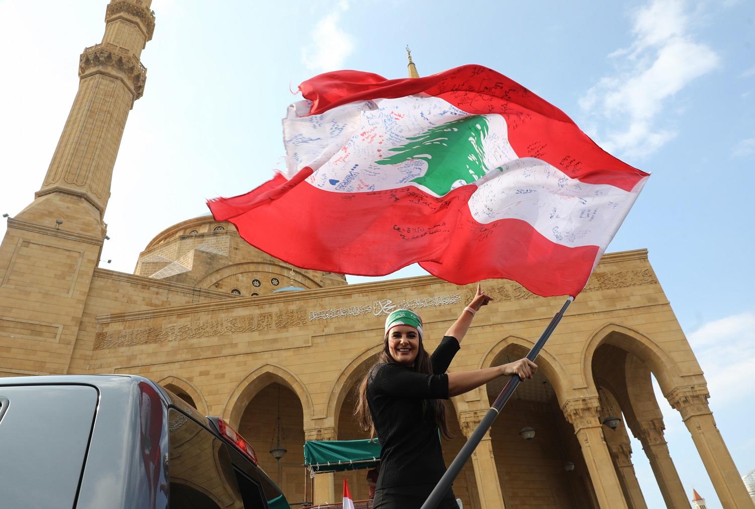 متظاهرة لبنانية تحمل علم بلادها في بيروت. أ ف ب 